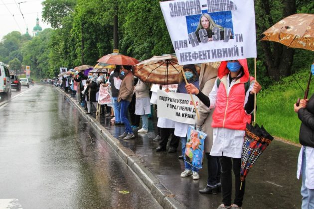На Дорогожичах лікарі в знак протесту стоять під дощем вздовж дороги – що вимагають