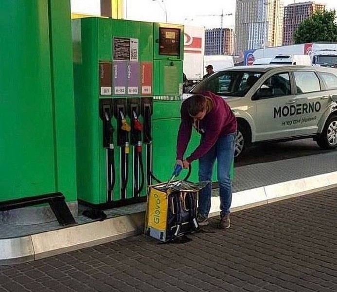 Фото дня: у столиці кур’єр Glovo “заправлявся” бензином у фірмовий рюкзак